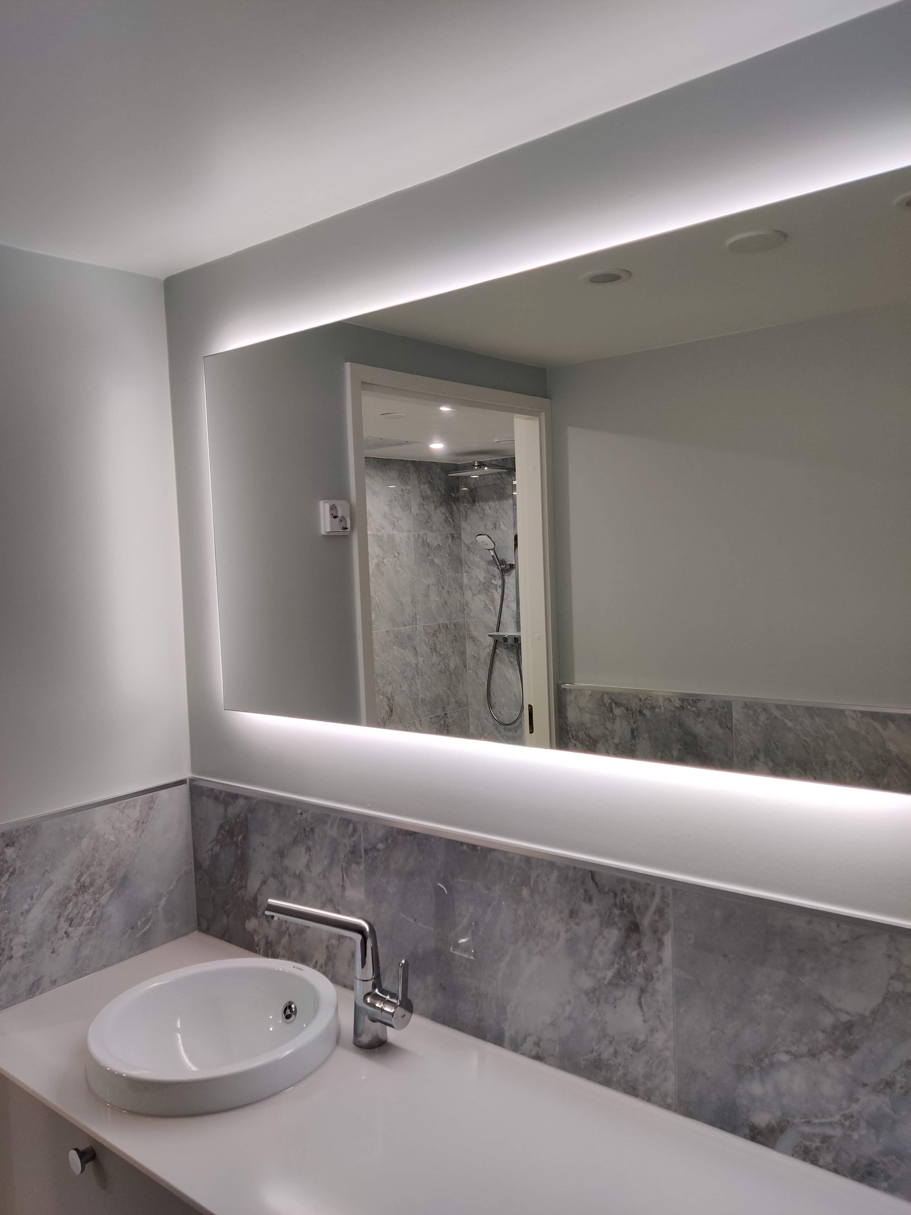 A bathroom renovation with a mirrored cabinet and grey stone-look wall tiling, completed by Pohjola Constructions