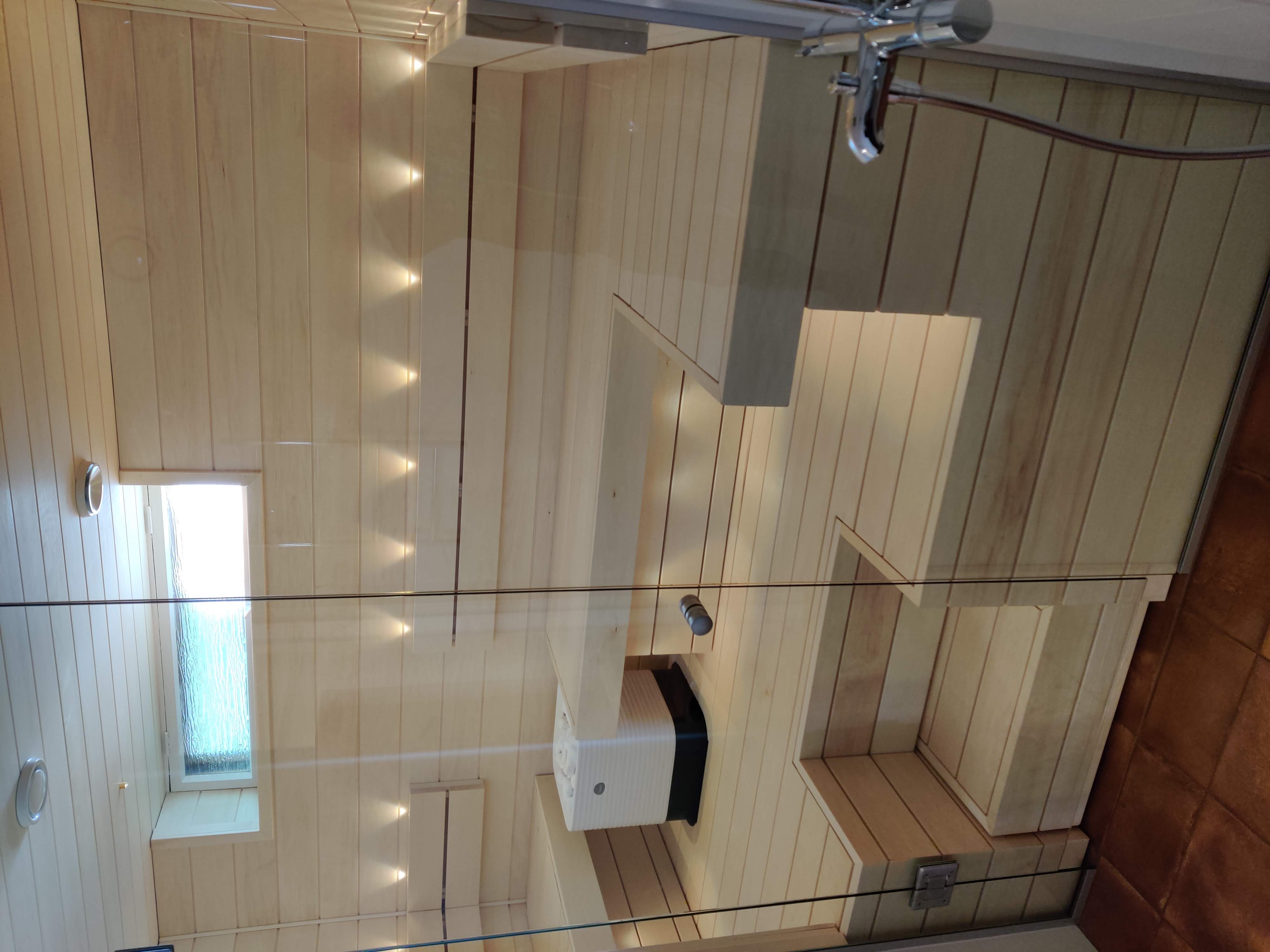 A timber-lined shower and sauna space with chrome fittings, completed by Pohjola Constructions