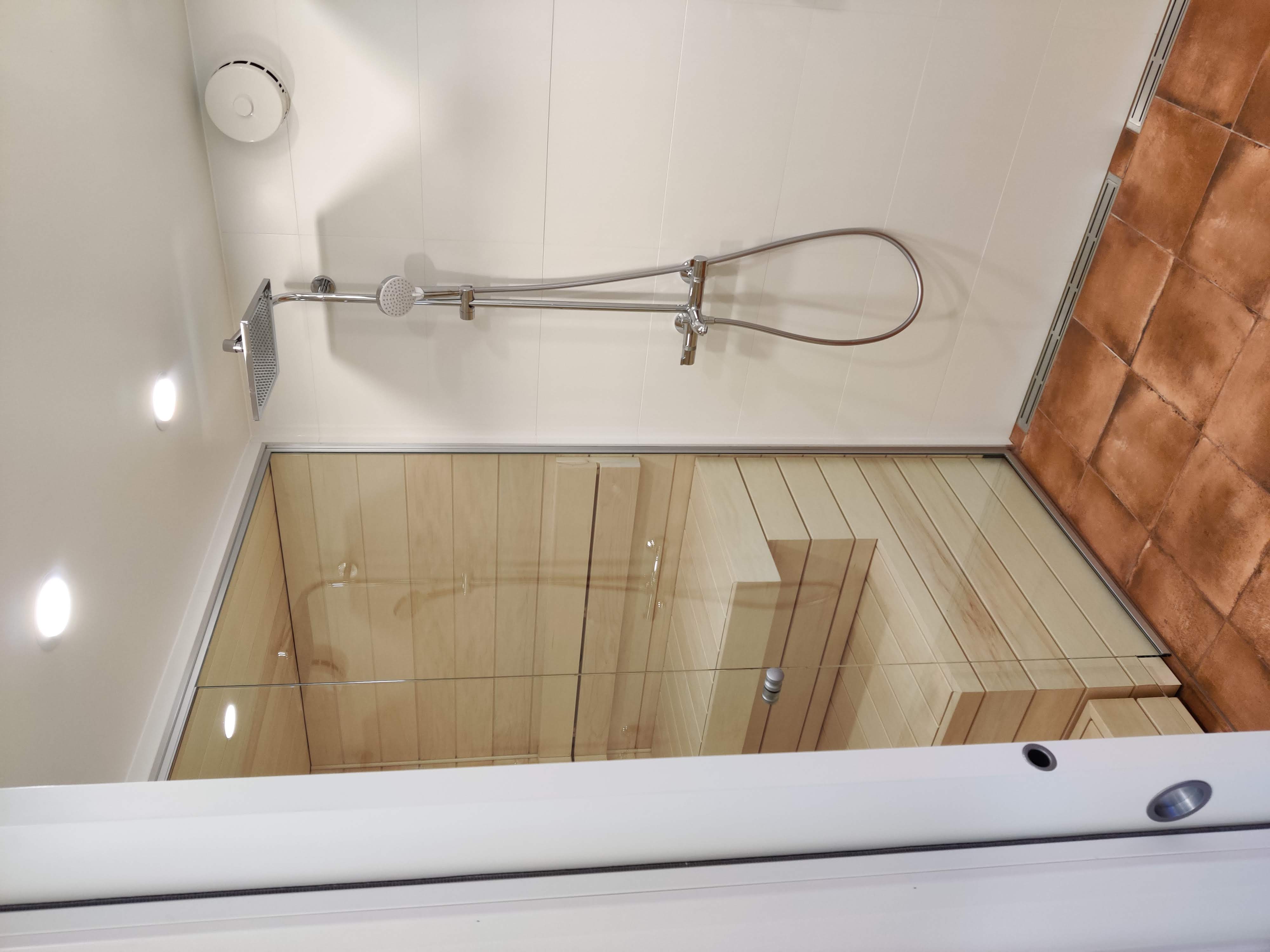 A timber-lined sauna and shower renovation with terracotta floor tiling, completed by Pohjola Constructions