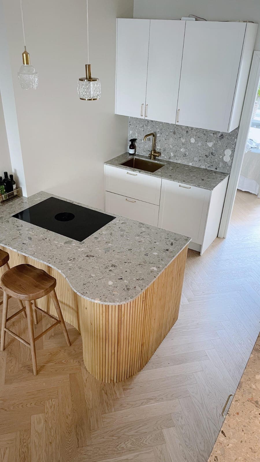 A renovated kitchen with a terrazzo-look stone benchtop and timber island, completed by Pohjola Constructions
